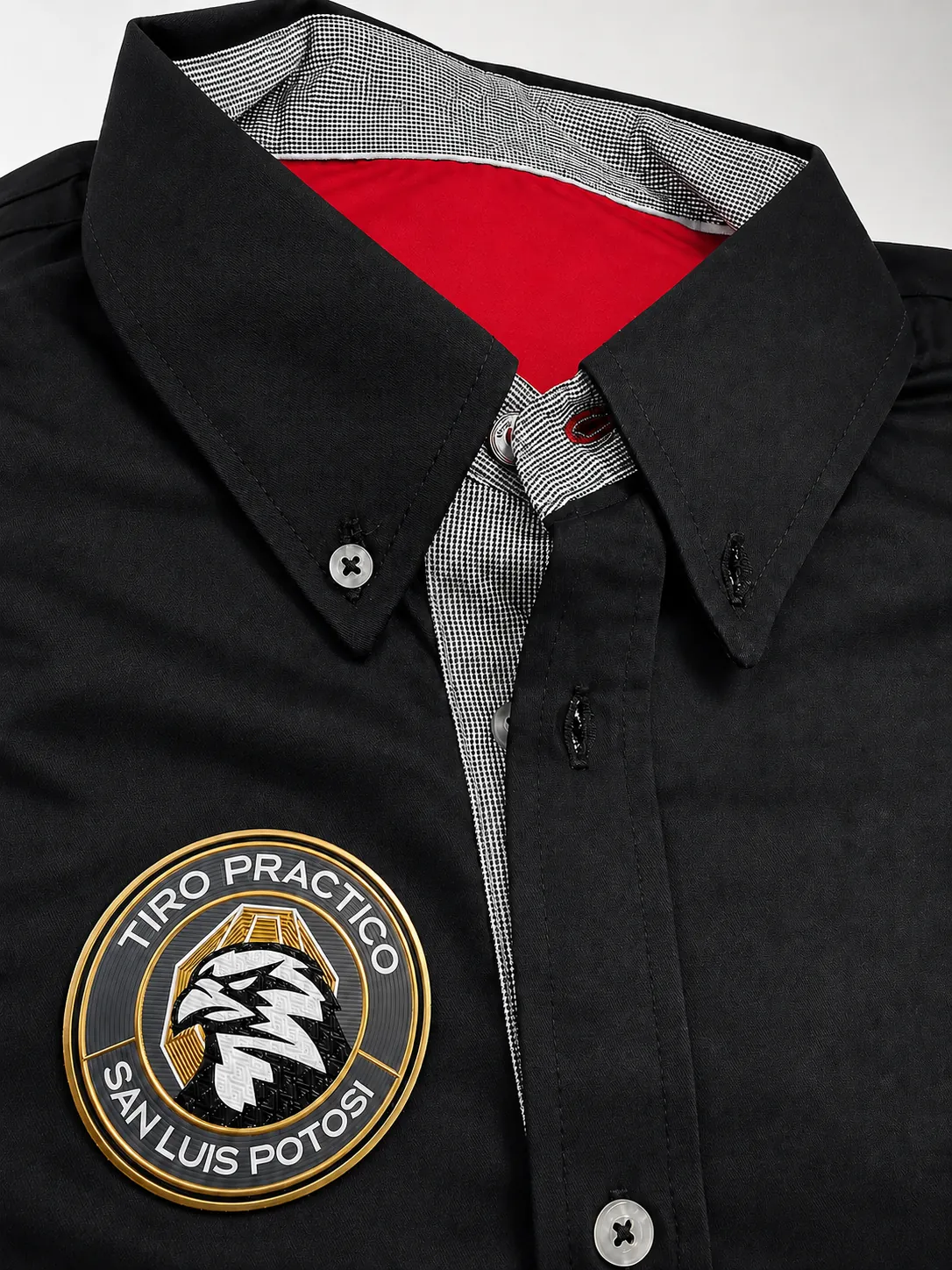 Detalle de emblema TPU circular con relieve dorado sobre camisa negra