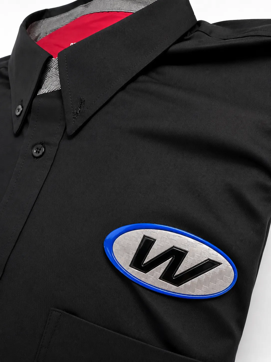 Detalle de emblema TPU ovalado con acabado metálico sobre camisa negra